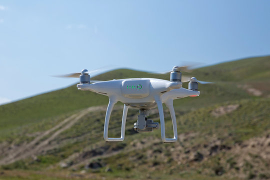 Drone quad copter with high resolution digital camera on the sky .White drone with digital camera flying in sky over mountain Drone with high resolution digital camera.