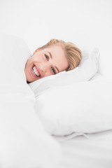 Cheerful pretty model relaxing in cosy bed