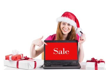 Festive redhead shopping online with laptop against sale advertisement