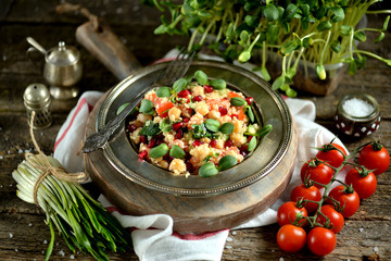 Healthy salad with couscous, chickpea, tomato, pomegranate and olive oil. Eastern cuisine.