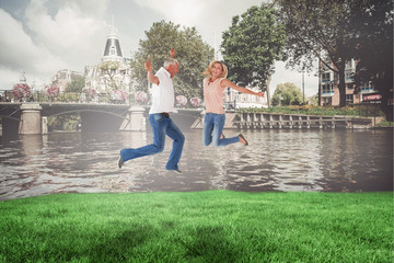 Excited couple cheering and jumping against sunny day by the river