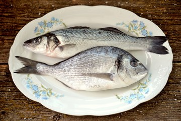 Fresh raw fish seabass and Dorado an old wooden background.