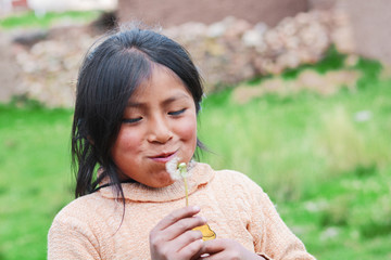 Little native american girl blowing dandelion flower.