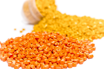 Plastic resin. Plastic pellets. Orange green and pink Polypropylene granules scattered on the lab...