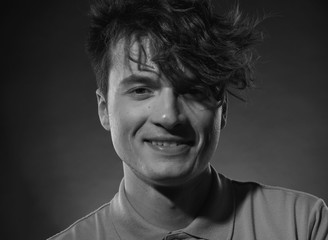 Face with a beautiful young guy's smile close-up with a long bangs. Black and white male portrait.