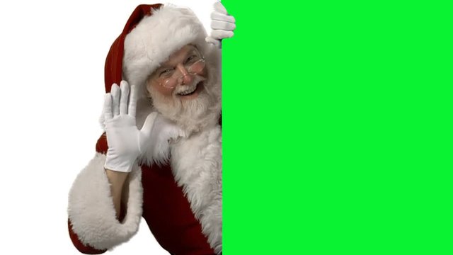 Santa Waving From Behind A Green Screen For Your Logo/text