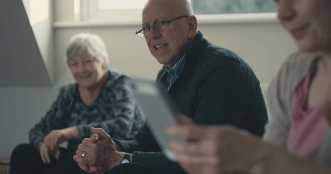 Senior couple and adult daughter with smartphone at home
