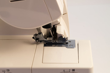 The main working segment of the overlock (electric sewing machine for seam processing) is a foot with two needles, into which white threads are threaded.