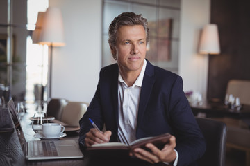 Businessman writing on diary