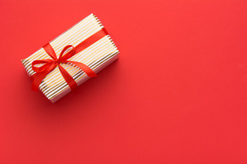 Fototapeta premium Hands holding wrapped gift box with colored ribbon as a present for Christmas, new year, mother's day, anniversary, birthday, party, on white background, top view. Present for a colleague at work.