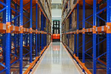 Electric forklift between large shelving in a modern storage building.