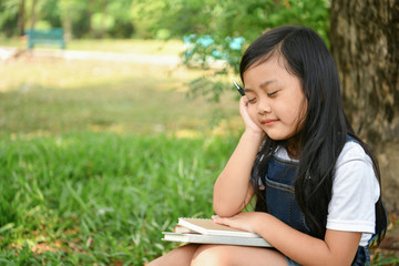 Education Concepts. The girl is reading a book in the garden. Beautiful girl is seriously studying. Beautiful girls are happy learning.