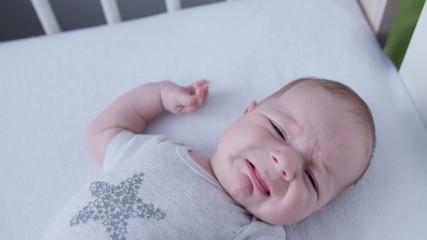 Baby's lying on a white linen in bed at home. Close-up shot