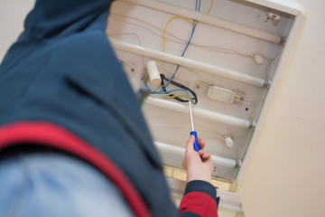 Electrician man worker in uniform installing ceiling fluorescent lamp