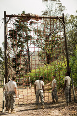 Military soldier climbing rope during obstacle course