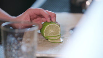 Close-up of clean hands slicing a lime in the kitchen