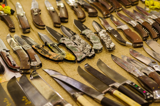Folding and tourist knives on rough fabric, A variety of folding knives