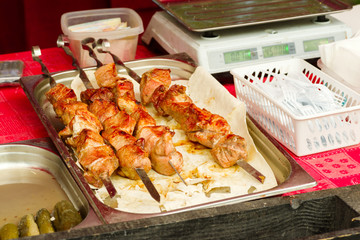 Fried pork meat on skewers lies on the counter during street trade