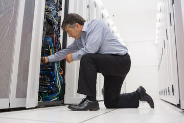Technician kneeling and repairing a server with his hands