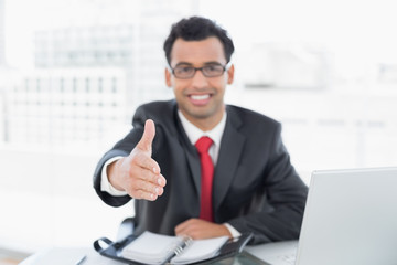 Obraz premium Blurred businessman offering a handshake at office desk