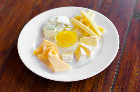 Cheese plate. Assortment of various types of cheese on wooden cutting board.