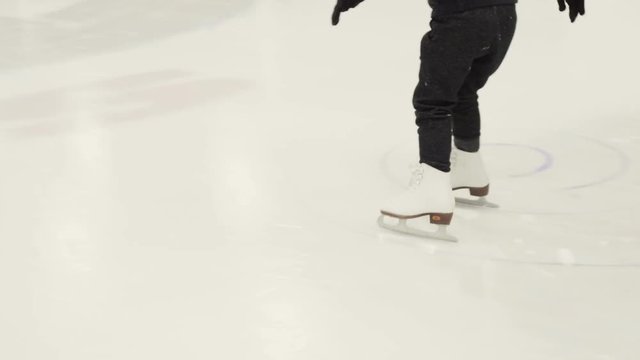 Little girl learning how to ice skate on indoor ice skating rink