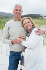 Happy senior man embracing woman at beach