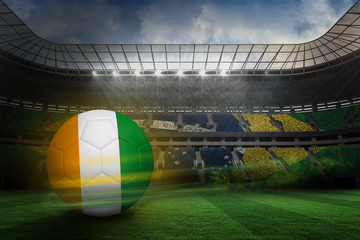 Fototapeta na wymiar Football in ivory Coast colours against large football stadium with brasilian fans
