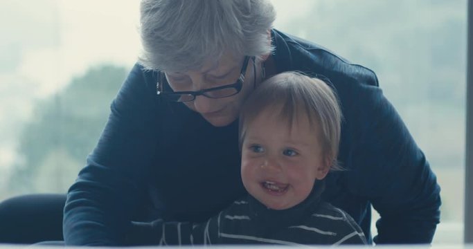 Grandmother with grandson at home by window
