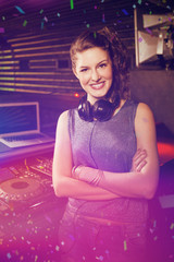 Obraz na płótnie Canvas Pretty female DJ standing with arms crossed against flying colours
