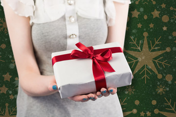 Woman offering a wrapped gift against snowflake wallpaper pattern