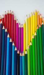 Colored pencils arranged in heart shape on white background