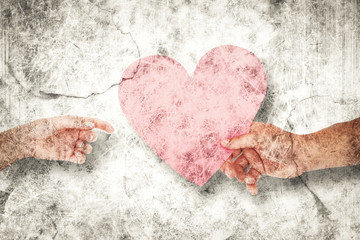 Couple passing a paper heart against grey background