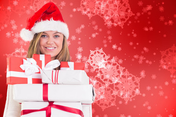 Festive blonde holding pile of gifts against digitally generated delicate snowflake design