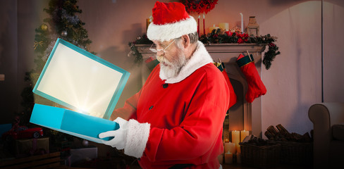 Santa Claus opening gift box against christmas tree with presents near the fireplace