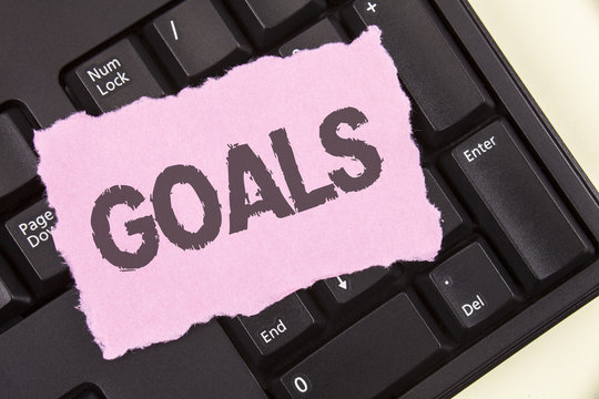 Conceptual hand writing showing Goals. Business photo showcasing Desired Achievements Targets What you want to accomplish in the future written on Tear Sticky note paper plain background Keyboard.