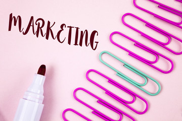 Writing note showing  Marketing. Business photo showcasing Advertising Selling products from a company To promote something written on Plain Pink background Marker and Paper Pins next to it.
