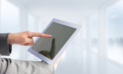 Businesswoman using a tablet pc against bright white hall with windows