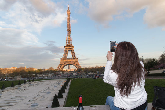 Woman taking photo of Eiffel Tower in Paris, France with cellphone