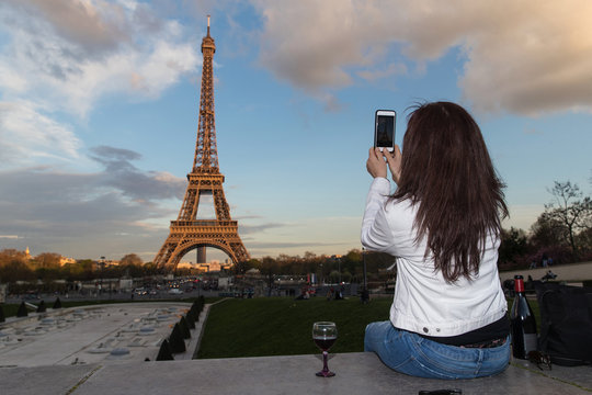 Woman taking a photo of the Eiffel Tower with cellphone