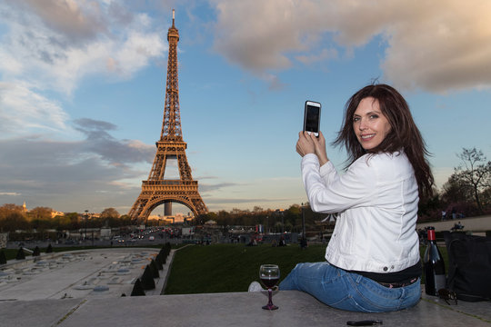 Woman taking photo of Eiffel Tower with her smartphone