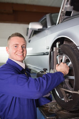 Smiling mechanic repairing a car wheel