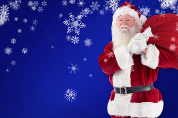 Santa carries his red bag and smiles against blue