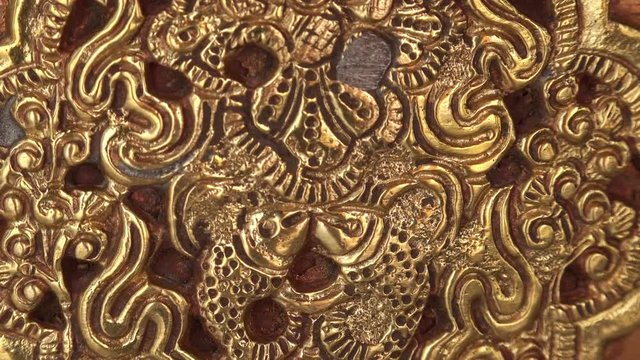 Close-up of beautiful traditional decorative Buddhist ornament or pattern covered with gold. Gorgeous golden Tibetan ornate decoration or bas-relief carving in tiny details. Camera slowly zooms out.