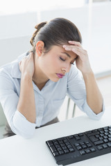 Businesswoman suffering from headache in front of laptop