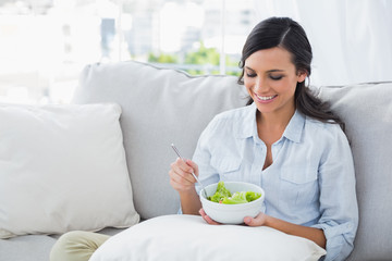 Obraz na płótnie Canvas Woman relaxing on the sofa eating salad