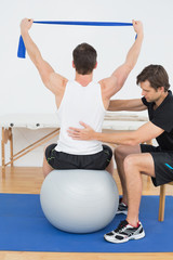 Naklejka premium Man on yoga ball working with a physical therapist