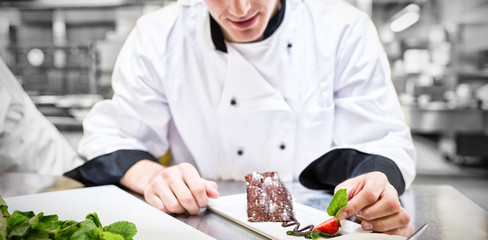 Chef putting mint leaf with his dessert in the kitchen © vectorfusionart