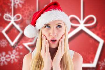 Festive blonde looking surprised with hands on face against blurred christmas background