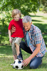 Happy father playing at the ball with his son 